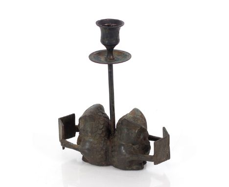 A vintage metal candlestick in the form of seated owls reading
