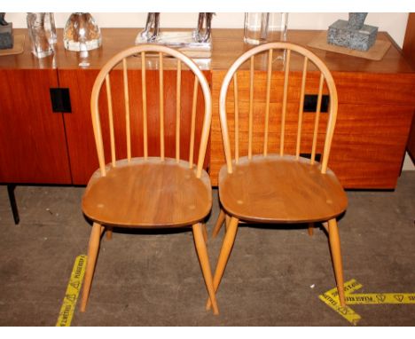 A set of Ercol stick back dining chairs, raised on rounded tapering supports