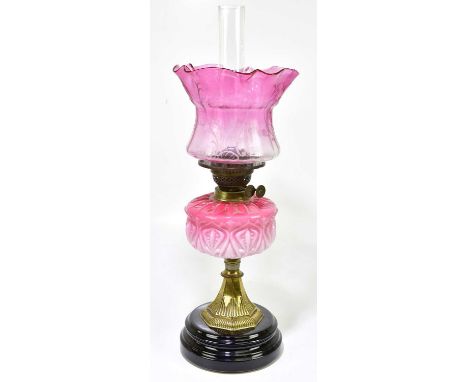 A Victorian glass oil lamp, the cranberry and clear glass shade with etched scrolling decoration above the moulded cranberry 