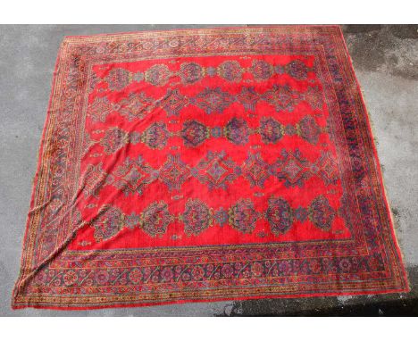 A large hand knotted carpet with geometric decoration and symbols, on a predominantly red ground, approx 470 x 430cm.Conditio