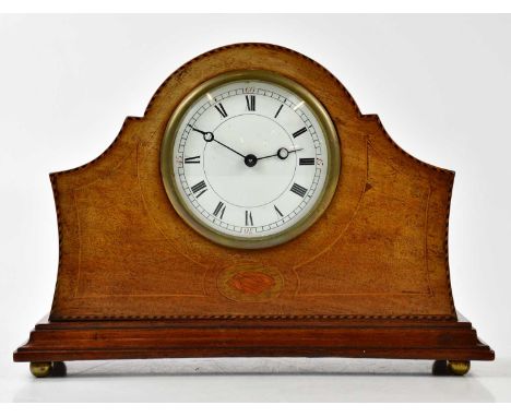 An Edwardian inlaid mahogany mantel clock, the arched top above the enamel dial set with Roman numerals, on four brass ball f