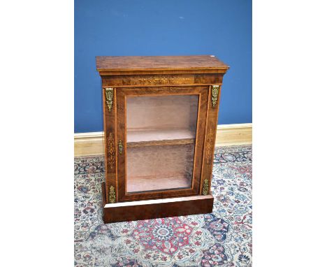 A Victorian inlaid walnut pier cabinet with applied gilt metal scrolls with floral detail flanking the single glazed door on 