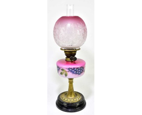 A Victorian oil lamp, the globular cranberry and milk glass shade with etched floral decoration above the painted cranberry a