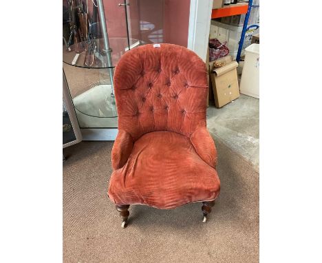 A Victorian nursing chair upholstered in a salmon pink button back material.