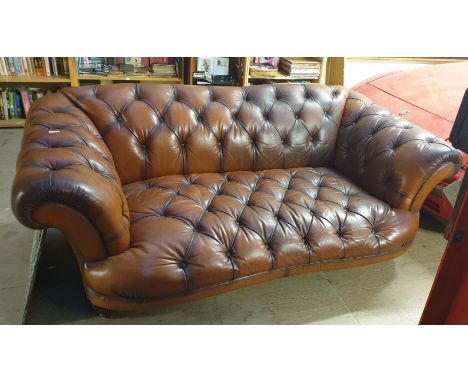 A brown leather three seater settee with button back upholstered seat, back and arms on reeded legs 