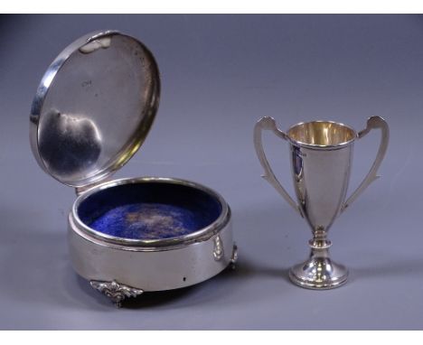 SILVER RING BOX, circular, Birmingham 1942 (some dents overall) and a miniature silver twin-handled trophy cup, 0.6 ozs, Birm