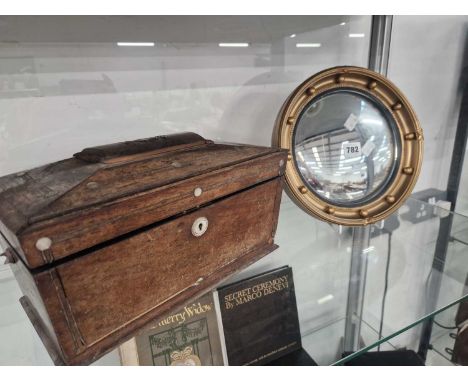 A small convex mirror within a gilt beaded frame and together with a sarcophagus tea caddy