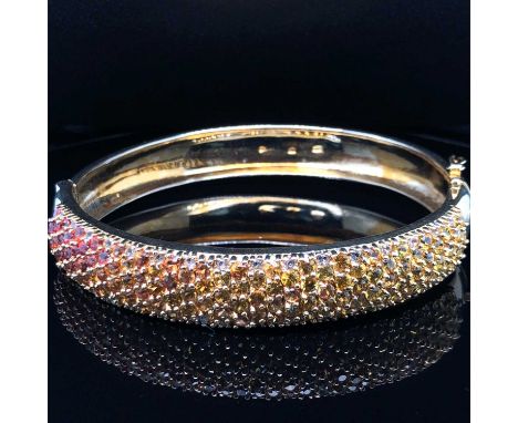 A multi-gemset silver gilt hinged bangle. Unhallmarked, stamped 925, assessed as silver. Weight 34.6 grams. 