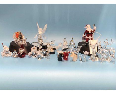 Twenty-one Swarovski glass Christmas-themed ornaments, including a deer, a star, three moose, a sled of presents, Santa Claus