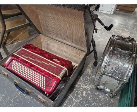 A piano accordion and a drum on stand.