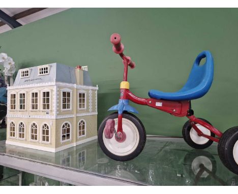 A modern dolls house together with a childs tricycle.