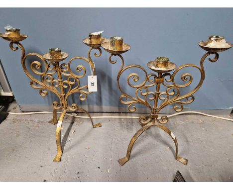 A pair of gilt iron strapwork three light candelabra, the scrolls below the nozzles forming heart shapes above the tripods.  