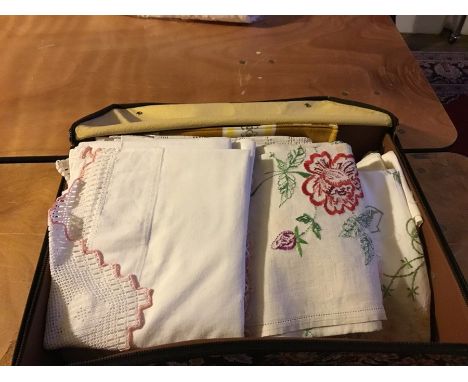 A tapestry suitcase, containing linen to include; a late 1950's table cloth, with a floral detail; a lace 1920's tablecloth, 