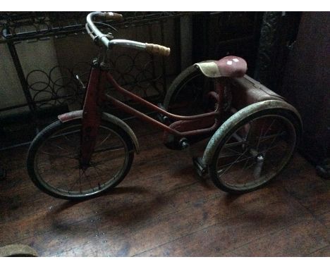 An early to mid 20th Century child's tricycle, padded seat, storage trunk to back, wheel arches, retaining original paintwork