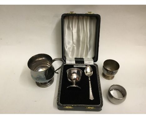 Boxed silver egg cup and spoon, along with a napkin ring (4)