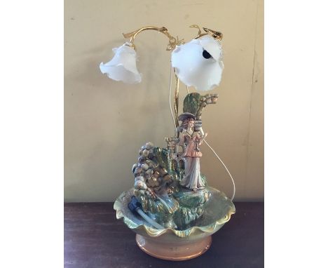 A late 20th century ceramic table lamp with figure next to a waterfall.