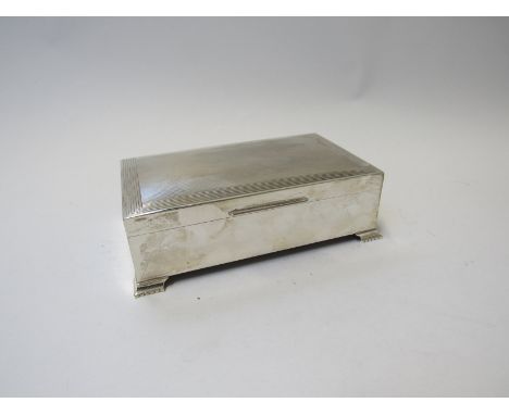 An MK silver cigarette box, engine turned detail and lined surround, on ogee style feet, Birmingham 1971, 16.5cm long 