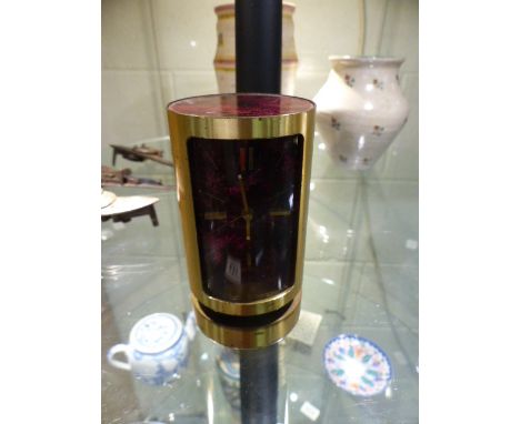 Swiza 8 Mid Century desk clock of cylindrical form. The Square face has a red marbled background with matching top. Sat on a 