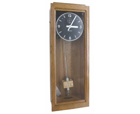 Inducta electric master clock,&nbsp;the 8.5" black dial with subsidiary seconds dial within a light oak glazed case, 35" high
