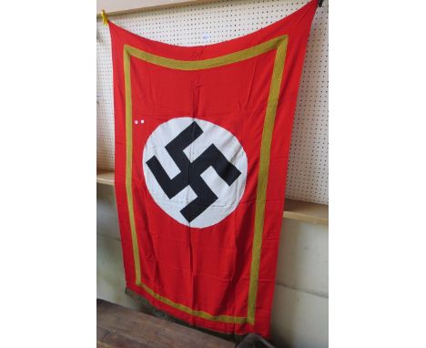 A WWII era German Nazi flag, central swastika in circle, gold surround and tassles, on red ground. Reputedly acquired from a 