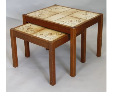 A nest of two G-Plan type tables, each with a leaf and berry decorated tile top, the largest 55cm wide.