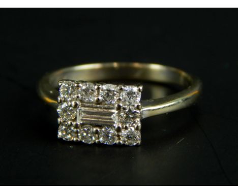 A diamond dress ring, with central baguette cut stone, surrounded by round brilliant stones, white metal, marked 18K, 2.8g al