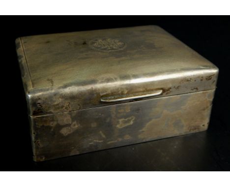 An Edwardian silver cigarette box, the engine turned lid decorated with a monogram, inscribed to the inside of the lid to W H