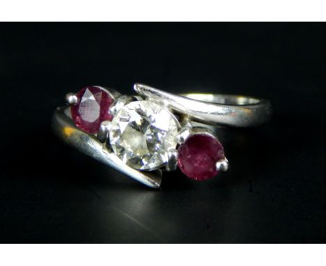 An 18ct white gold dress ring, set with ruby and diamonds, the central tension set diamond, approx 0.68cts, flanked by two ru