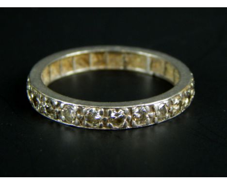 An eternity ring, set with white stones, in a white metal band, unmarked, 3.2g all in. 