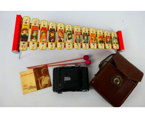 A vintage Zeiss Ikon camera contained in case and a child's glockenspiel decorated with fairytale characters. [W]