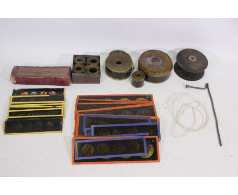 Various projector parts to include film reels, a quantity of glass slides, and similar. Glass slides include comic figures la