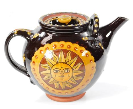 20thC slip ware teapot, decorated with a sun to either side, on a brown ground, 21cm H.