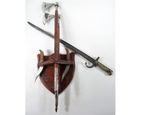A bayonet, with turned brass handle and shaped blade no. 63976, 68cm W, and two ceremonial axes on a shield back. (3)From the
