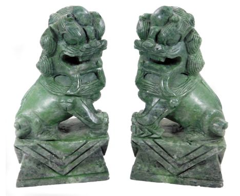 A pair of green jade finish dogs of fo, on shaped bases each typically carved 16cm H. (2)
