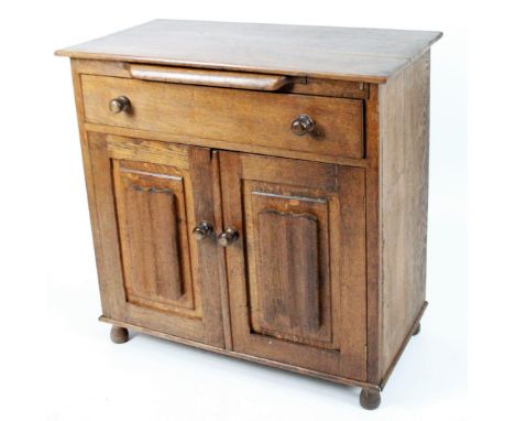 An early 20thC Lincolnshire oak cabinet, by A E Joiner, Boston, the overhanging top, above brushing shelf and frieze drawer a