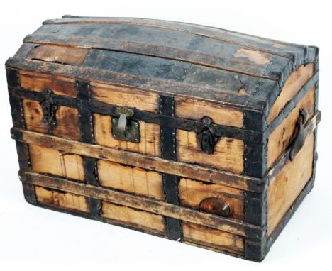 A late 19thC dome topped trunk, with wooden and metal strap work, elaborate escutcheon and plain interior with rope carrying 