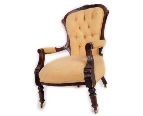 A late Victorian walnut armchair, with upholstered button back, arms and seat, carved scroll arm supports and castors, in (la