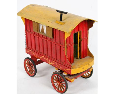 A 20thC wooden model of a traveller's caravan, with fixed roof, the main body painted red with yellow highlights on an articu