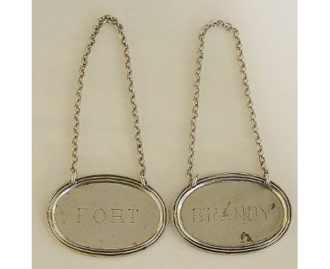 A pair of decanter labels, reeded edges encircling plain oval bodies engraved with 'Port' and 'Brandy' respectively, by Stoke