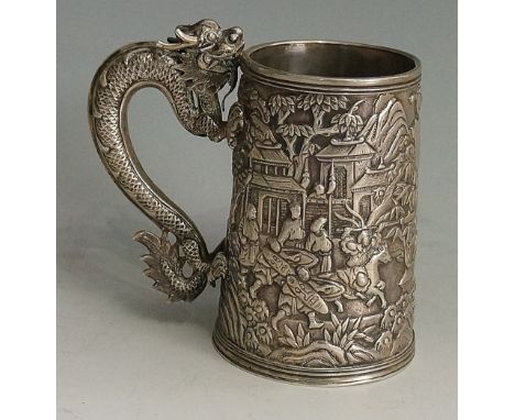 A Chinese silver tapering cylindrical mug with dragon handle, the body cast with figures amidst temple grounds, fighters on h