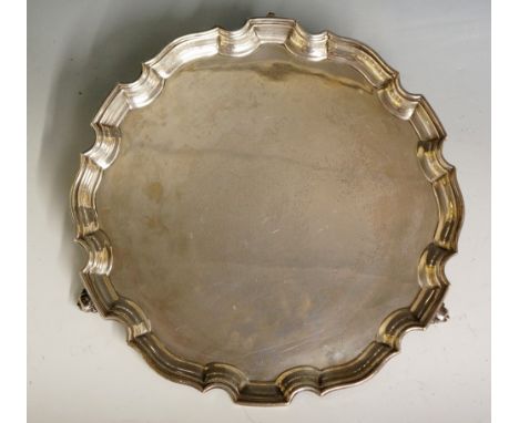 A plain silver salver with pie crust style edging, three ball and claw feet, the underside engraved 'F.B. 27.11.1912 - 8.12.6