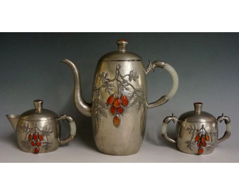 A Chinese pewter three piece tea service of rounded oval form the bodies applied leafage and berries inlaid carnelian cabocho