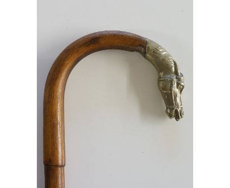 A crook handled walking stick, the end of the handle terminating with a cast white metal terminal in the form of a horse's he