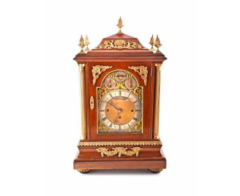 An Edwardian mahogany bracket clock. In a baroque style with stepped quadripartite pediment. With gilded finials, spandrels a