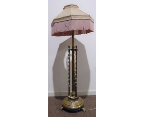 Early 20th century heavy brass standard lamp with triple barley twist column, lozenge decoration to the base, raised on scrol