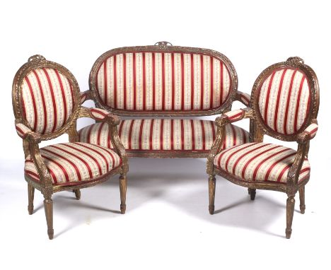 A 20th century French carved and gilded Regency stripe upholstered suite. With two fauteuils and a two-seat open arm sofa, al