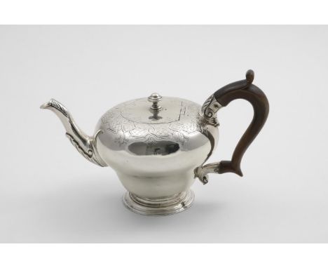A GEORGE III TEA POT of inverted baluster form with a leaf-wrapped spout, spreading circular foot and engraved decoration ove