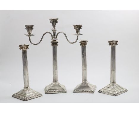 A SET OF FOUR EARLY GEORGE III CANDLESTICKS on stepped square bases with wave-like borders, fluted columns and Ionic capitals