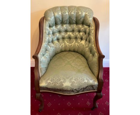 A mahogany framed deep button back upholstered armchair on front cabriole legs and porcelain casters. 
