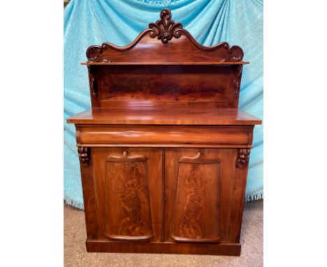 A mahogany chiffonier, carved shaped back with a single shelf raised on scroll supports, above one long drawer over a pair of